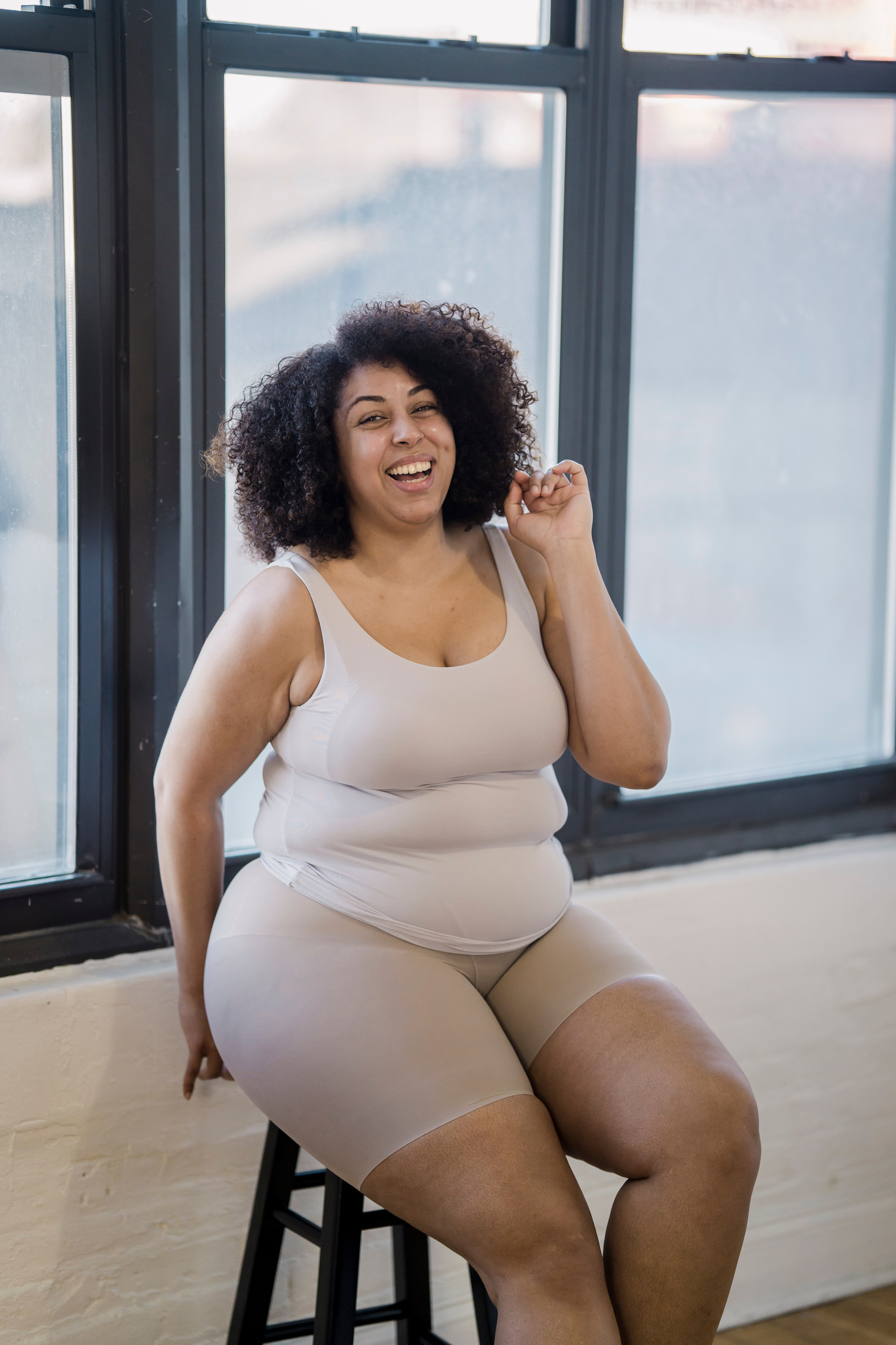 Happy overweight ethnic model in underclothes indoors